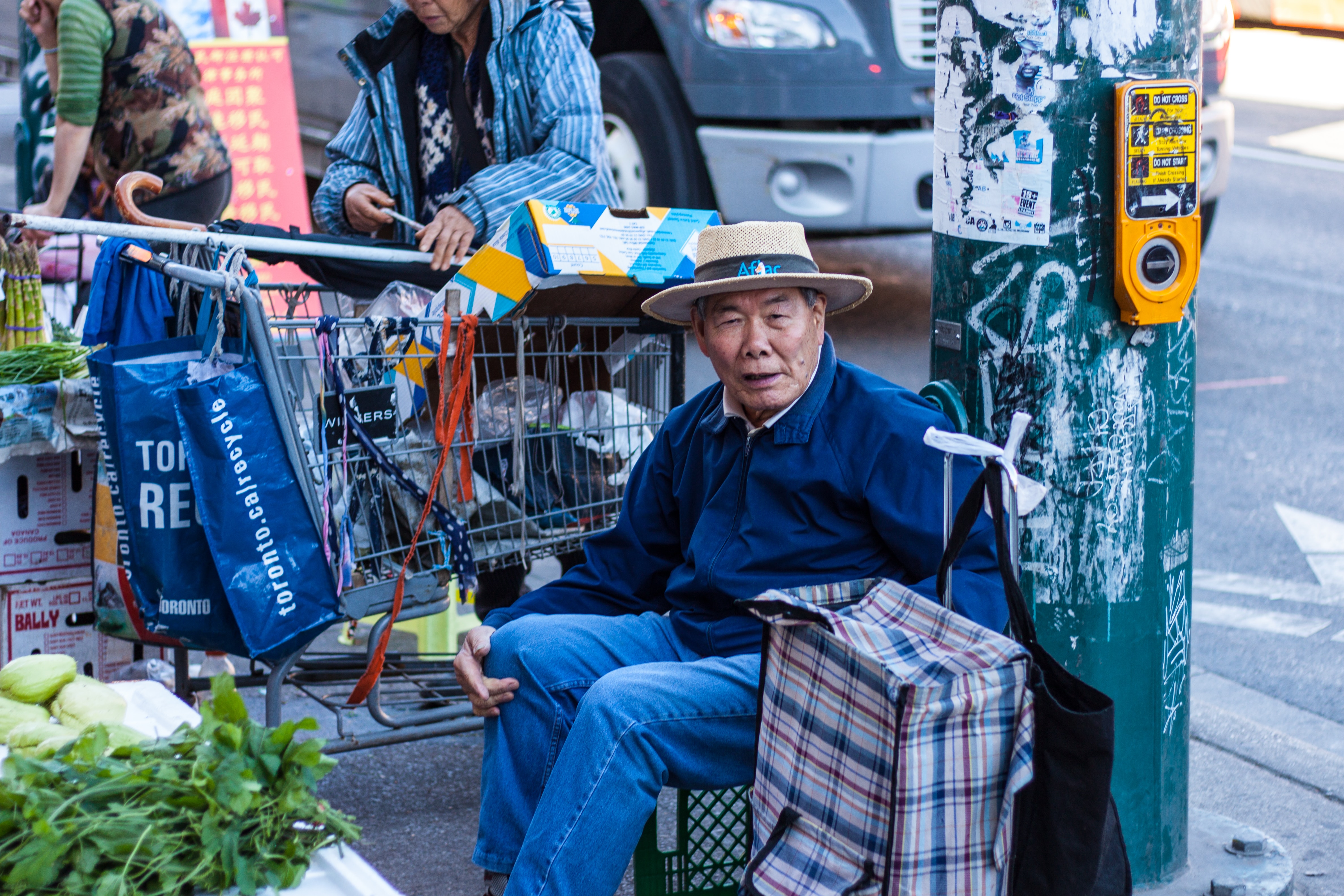 An elderly Asian man sits at a crosswalk in Toronto’s Chinatown