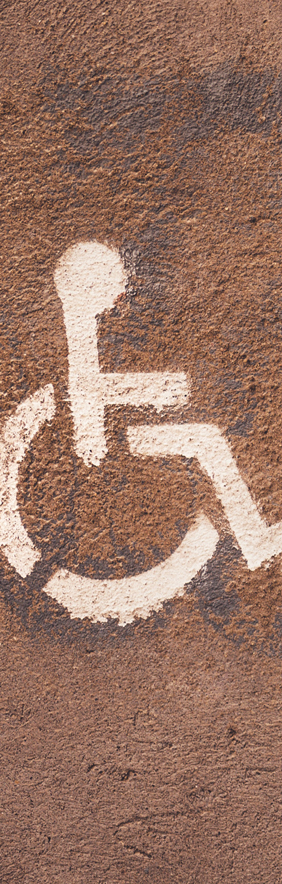 Représentation au pochoir (en blanc) d’une personne en fauteuil roulant sur une surface en béton