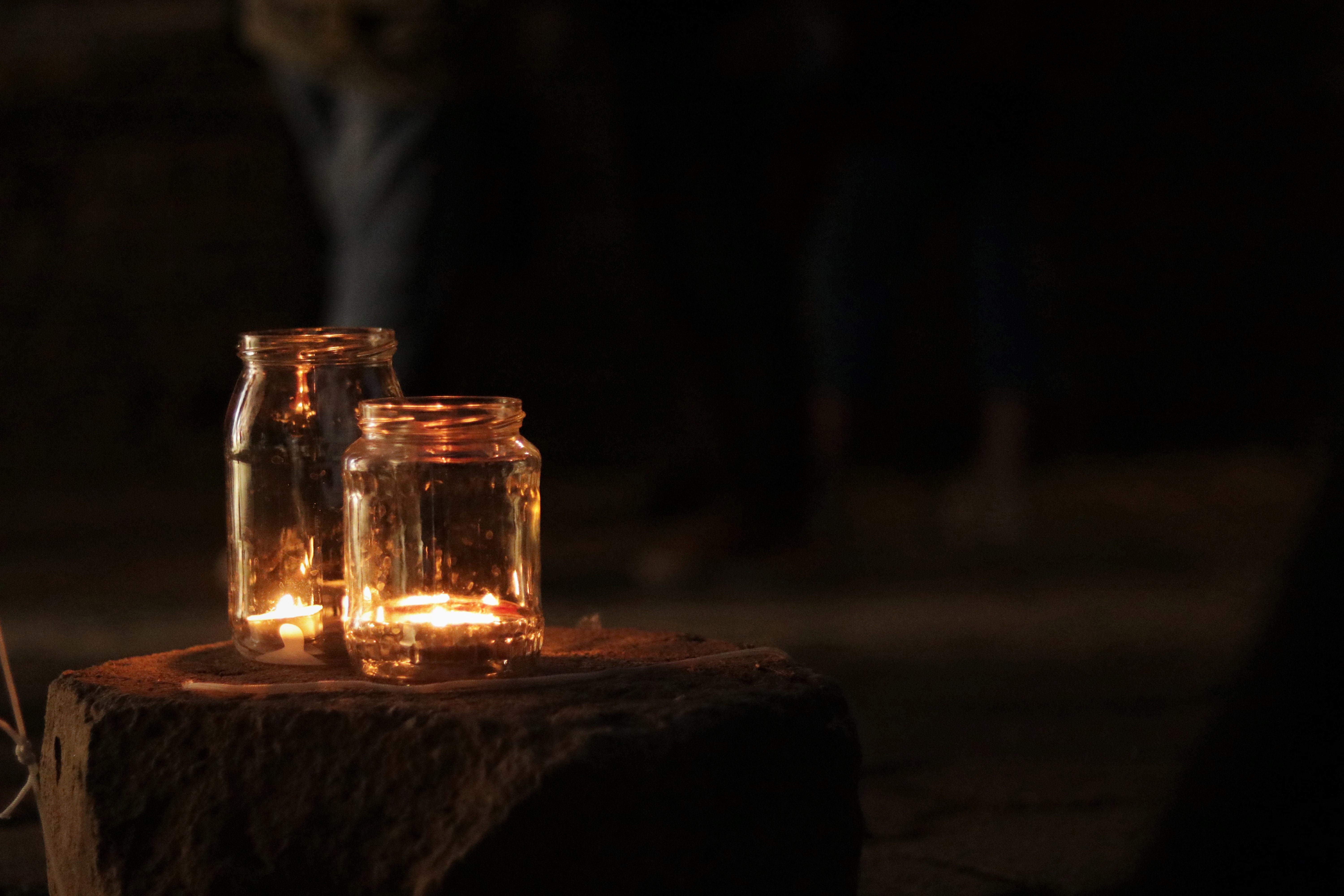 Two candles on a table glow against a dark background