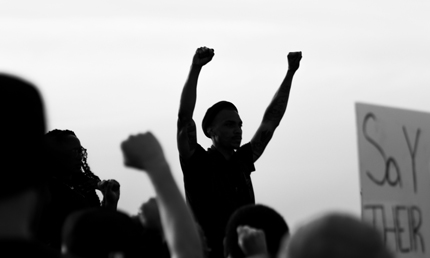 The silhouette of a man raising his fists amid a protesting crowd