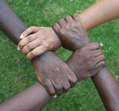 Four hands in a circle clasp each others’ wrists