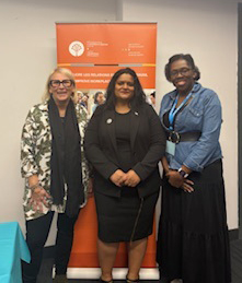 Andr&eacute;e, Sharon and Micha&euml;lle smile in front of a JLP banner.