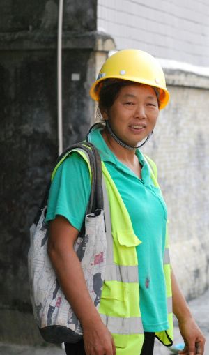 Une femme portant des vêtements de travail haute visibilité sourit à la caméra