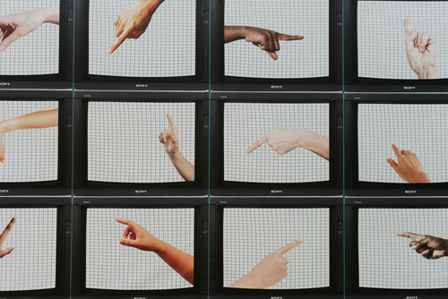 A grid of tv screens with hands of various shades in the process of signing. 