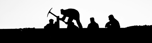 A line of road workers shot in silhouette